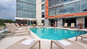 A modern hotel pool area with sun loungers, umbrellas, and a glass-enclosed pool. - Hyatt Place Washington DC/US Capitol (Washington)