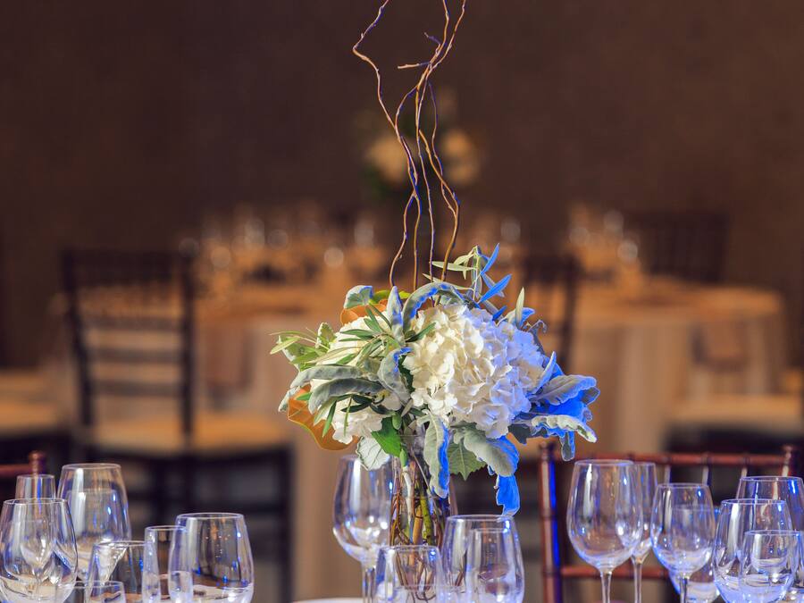 A table set for a formal dining event with a centerpiece of flowers and branches.