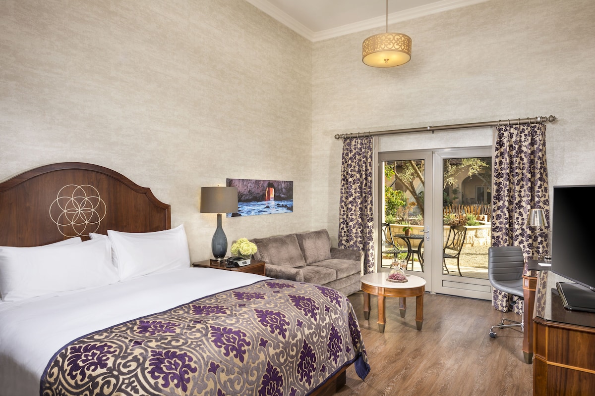 Una habitación de hotel con una cama grande, un sofá, una mesita y un televisor.