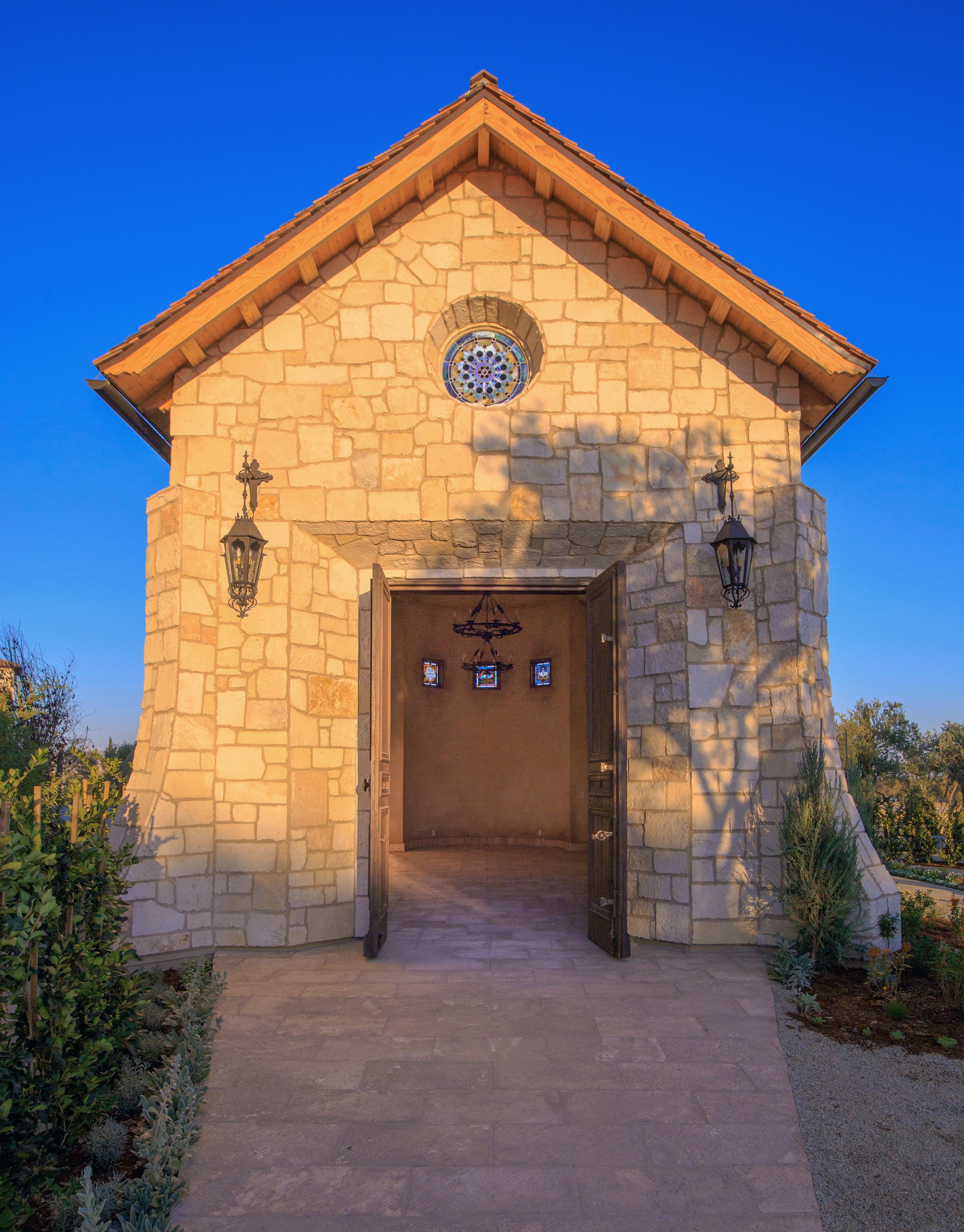 A stone building with a wooden door and two lantern-style lights on either side.
