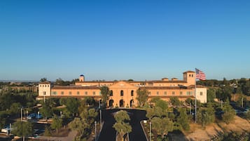 A large building with a central courtyard, a flag, and a dome structure in the background.