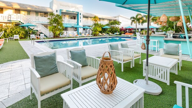 Ein Poolbereich mit weißen Liegestühlen, einem Pool und einem Gebäude mit der Aufschrift 'Vagabond Motel'.