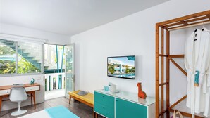 Ein modernes Hotelzimmer mit Bett, Schreibtisch, Fernseher, einem Holzgestell und einem Badezimmer mit Handtuchhalter.