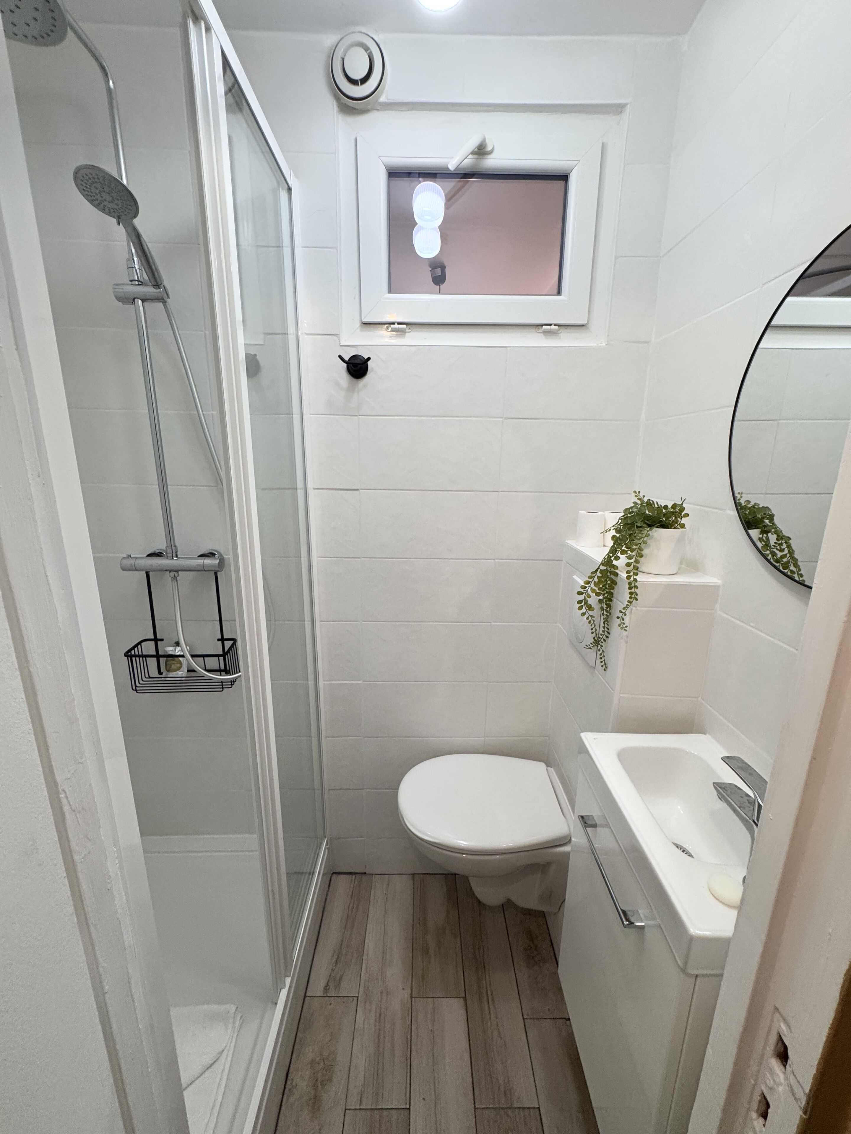 Un baño pequeño con ducha, inodoro y lavamanos.
