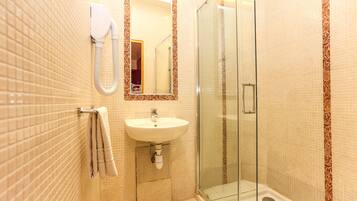 Une salle de bain équipée d’un lavabo, d’un miroir, d’un porte-serviettes et d’une douche à parois en verre.