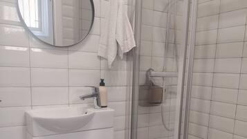 Een badkamer met een wit wastafelmeubel, spiegel en douchecabine.