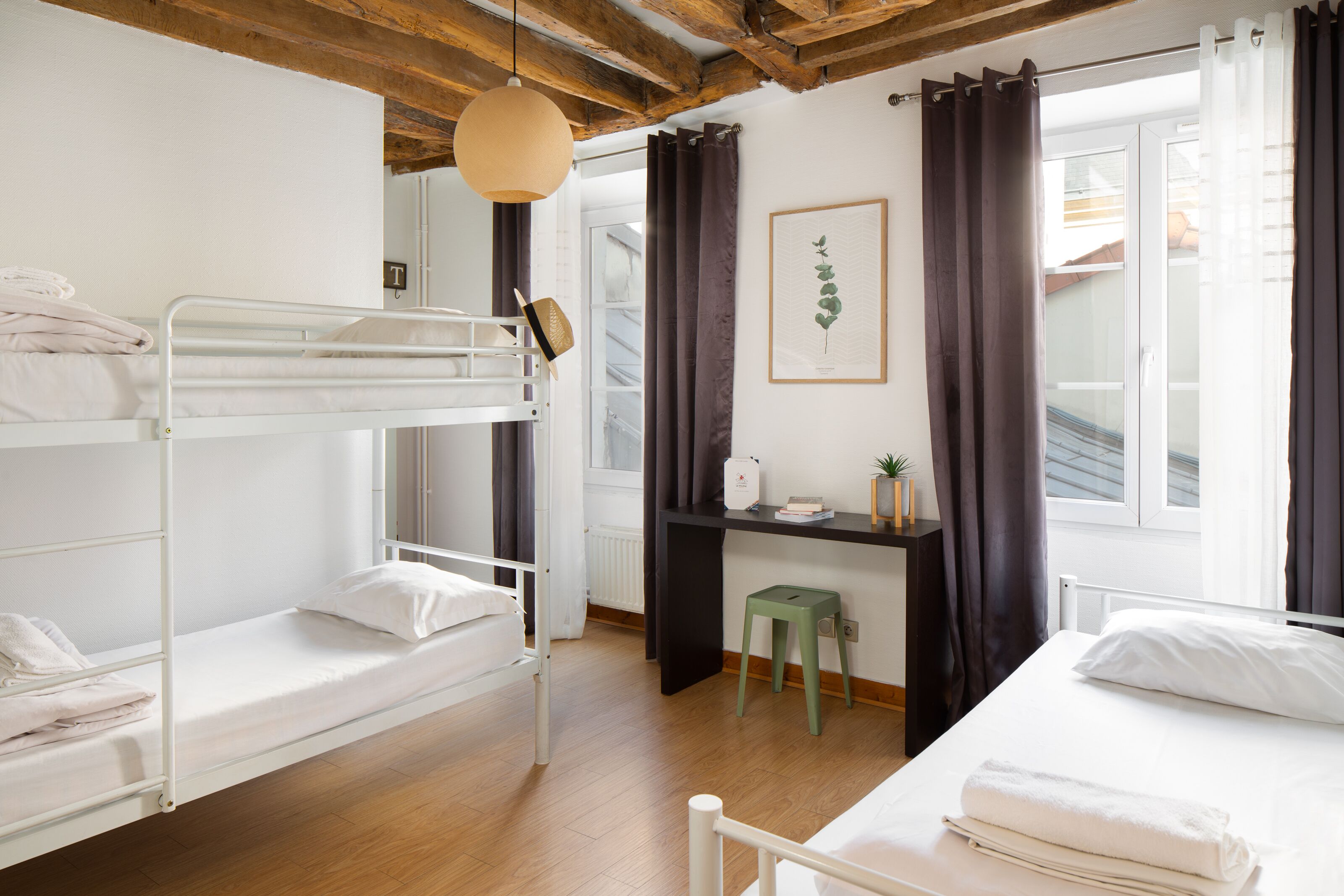 Un dormitorio con literas, un escritorio, una silla y una ventana con cortinas.