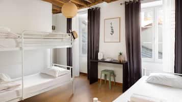 Un dormitorio con literas, un escritorio, una silla y una ventana con cortinas.
