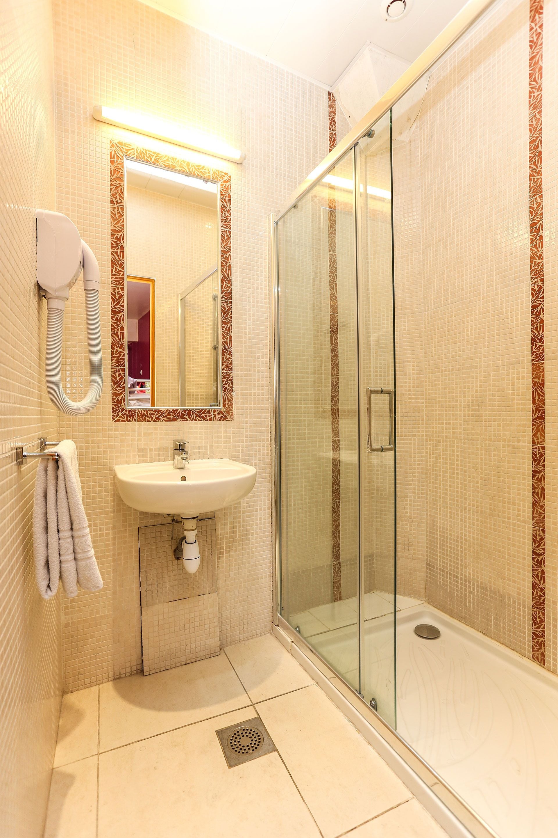 A bathroom with a glass-enclosed shower, a sink, and a towel rack.