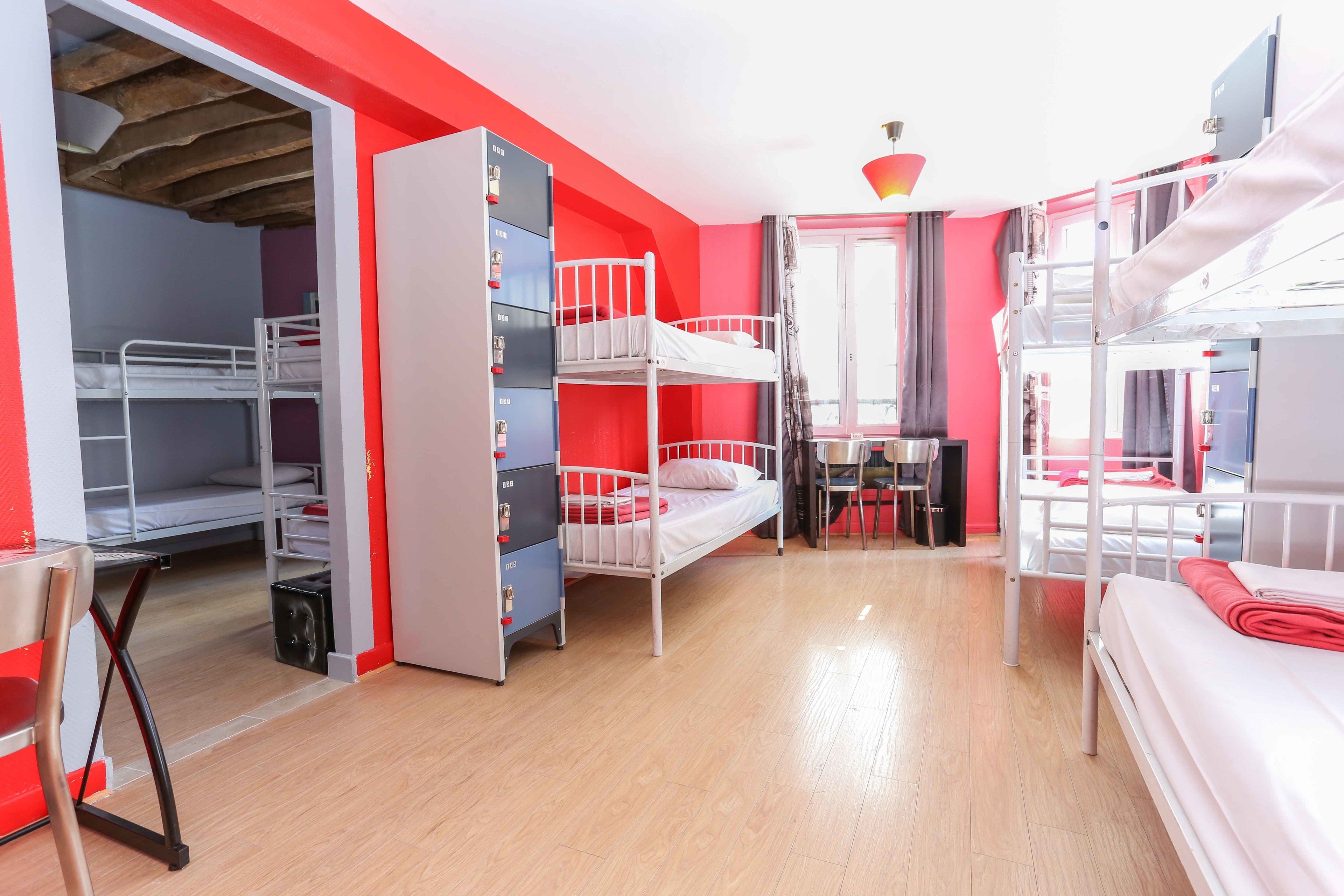 A dormitory room with bunk beds, a desk, and a chair.