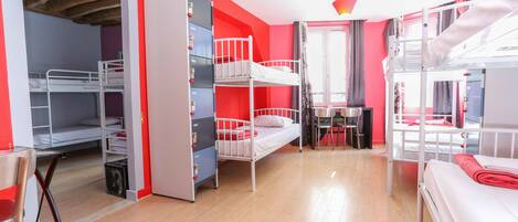 A dormitory room with bunk beds, a desk, and a chair.