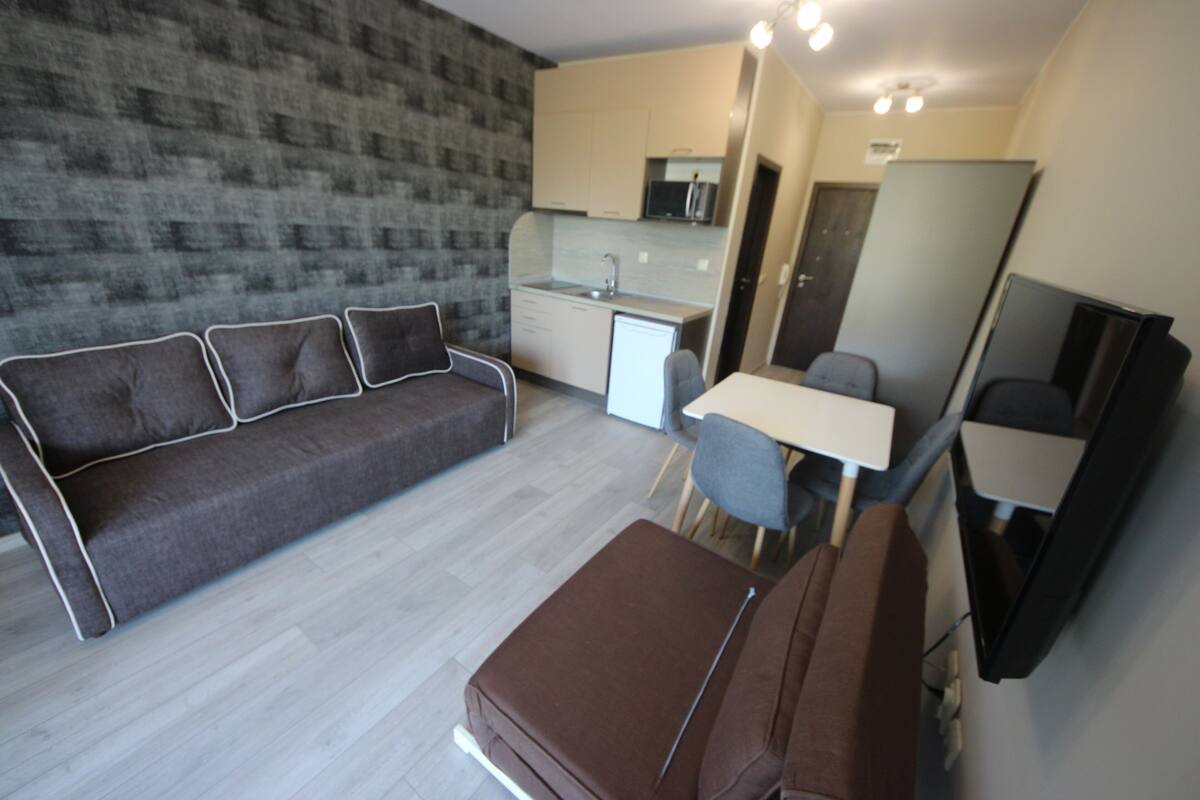 A modern living room with a sofa, a small table, and a brown ottoman.