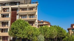 Un edificio residencial de varios pisos con balcones, unidades de aire acondicionado y un cielo azul despejado.
