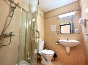 A bathroom with a glass-enclosed shower, a white toilet, and a sink with a mirror above it. - Menada Luxor Apartments (Sveti Vlas)