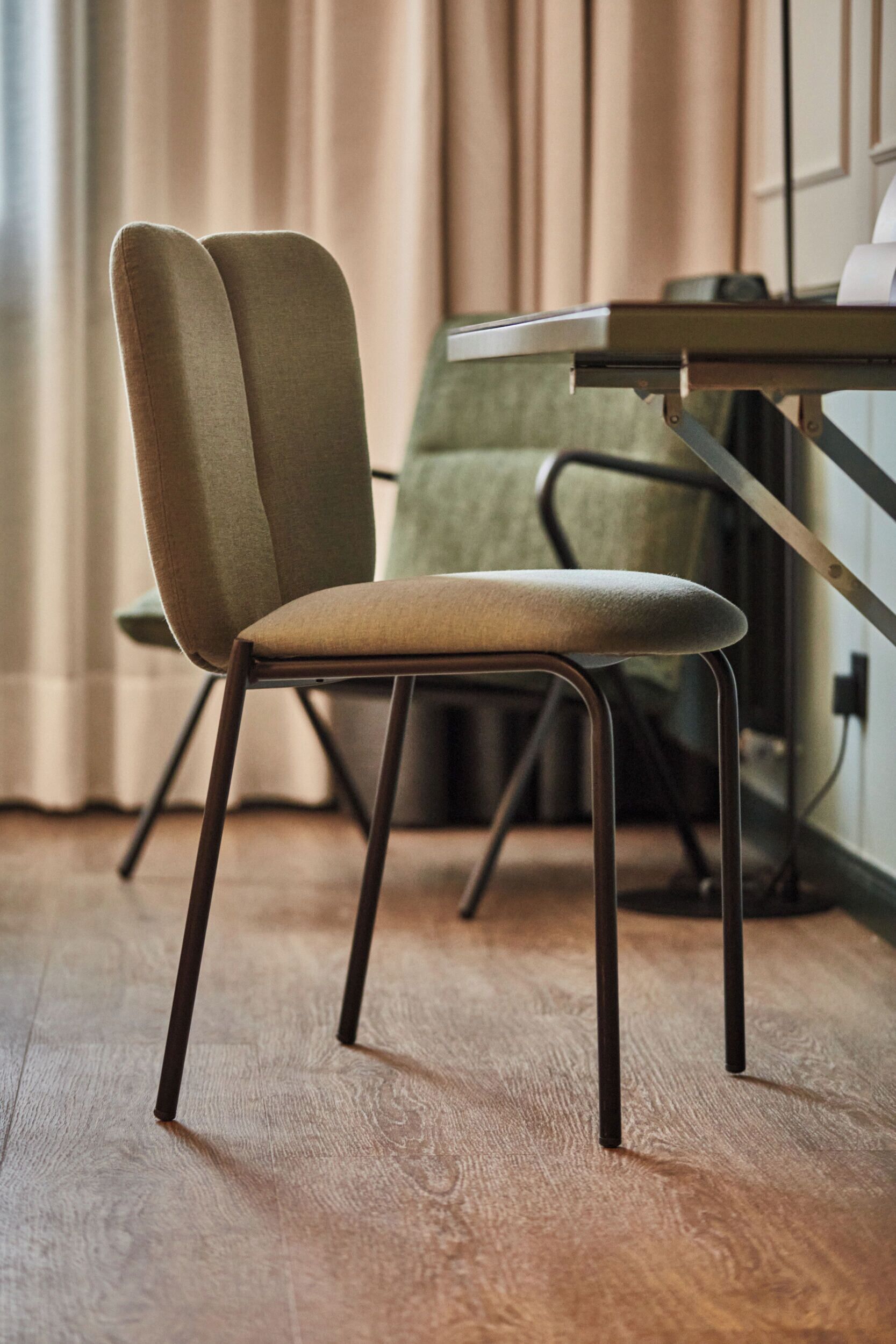 A modern chair with a cushioned seat and backrest, metal legs, and a wooden floor.