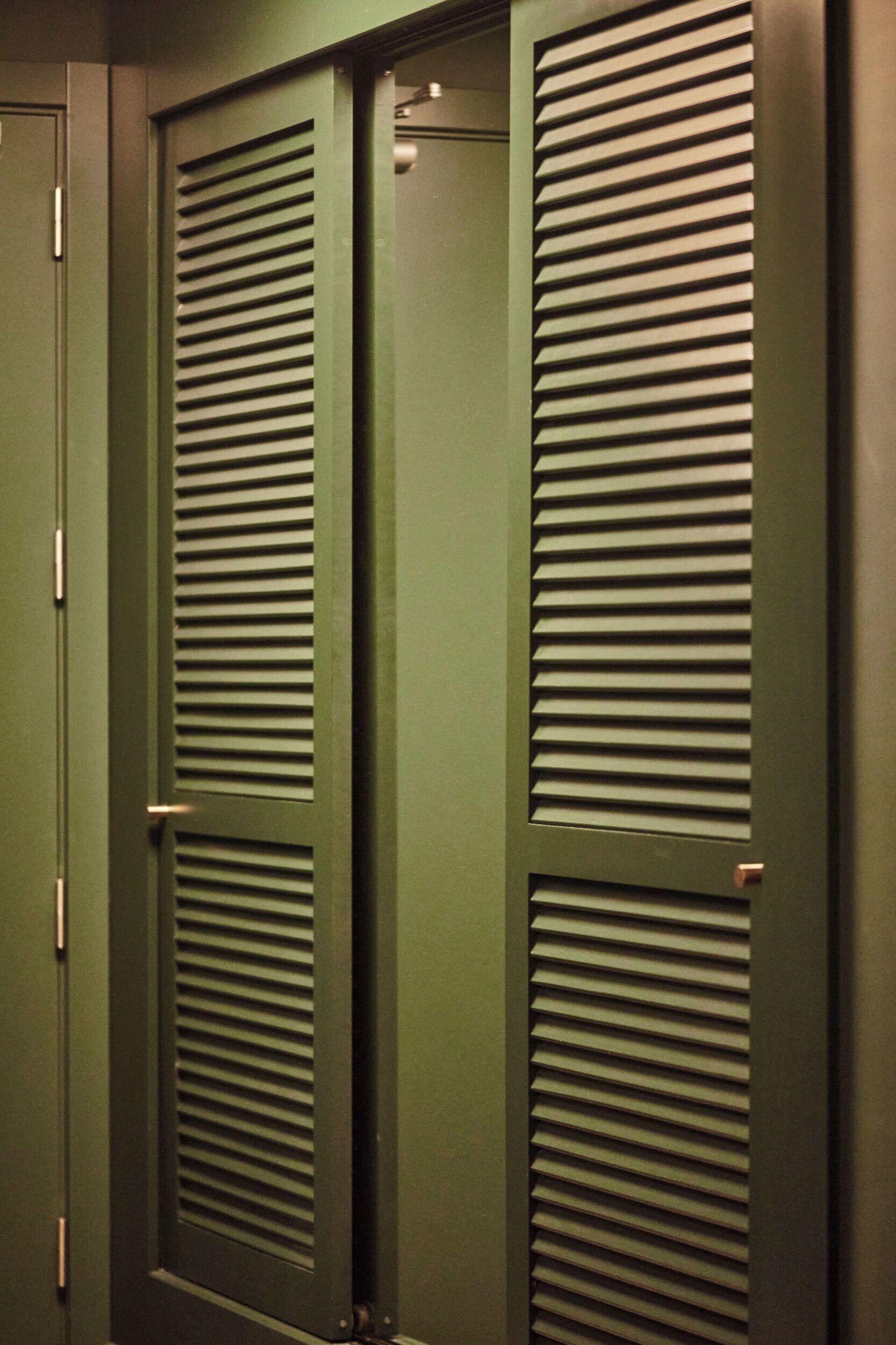 A set of green doors with horizontal louvered panels.