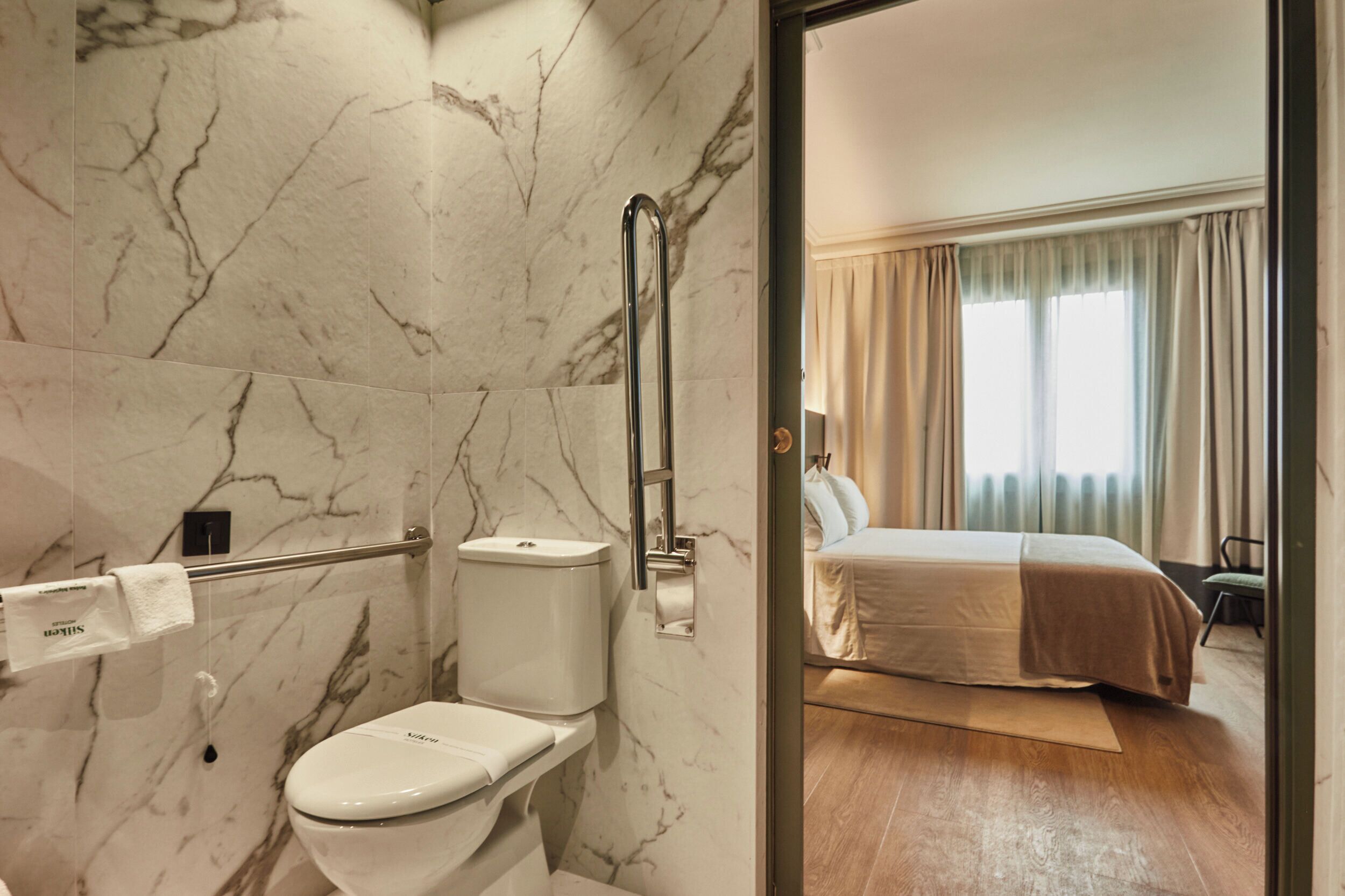 Un baño con inodoro, paredes de mármol y zona de ducha.