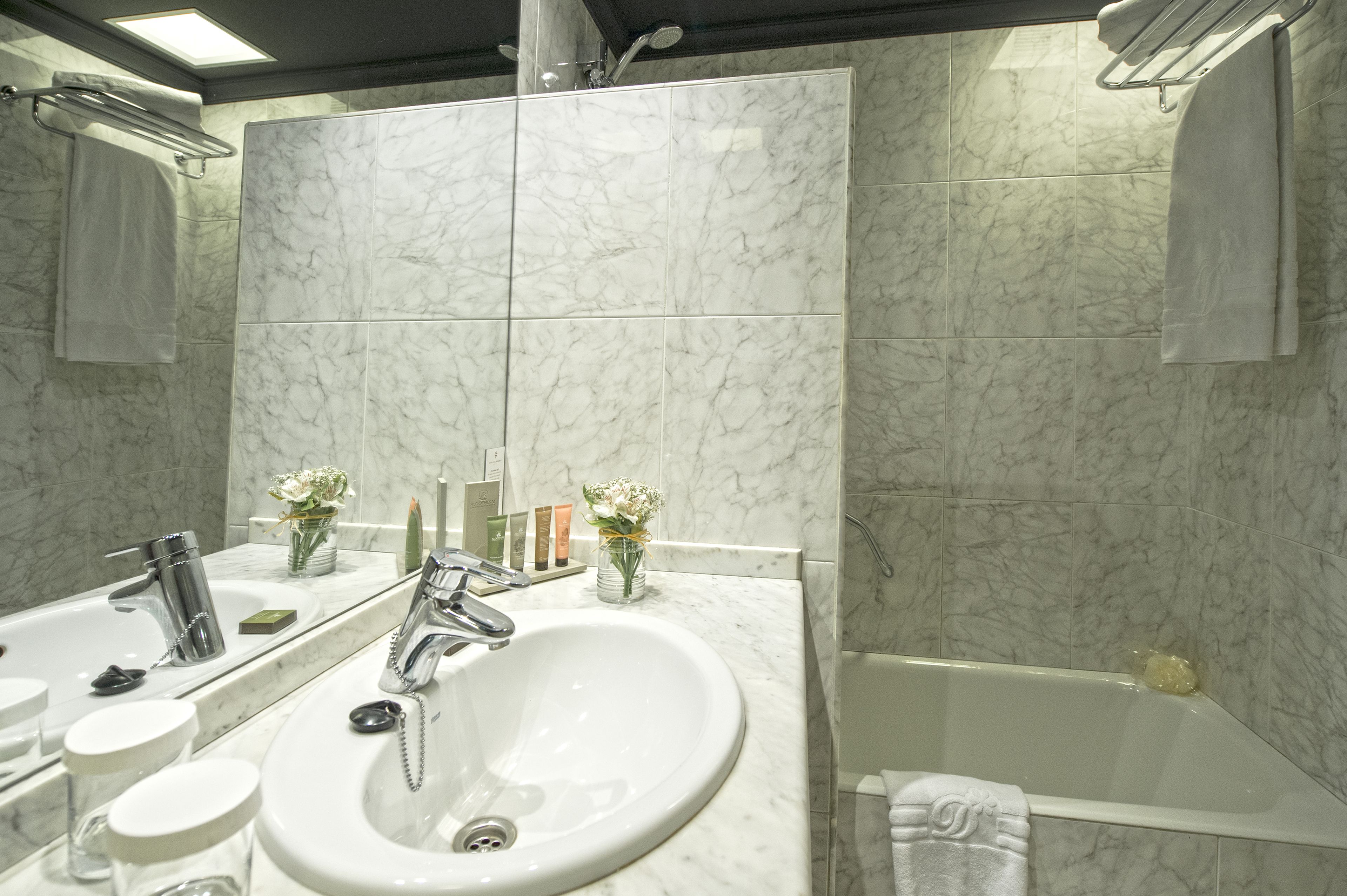 Une salle de bain avec un lavabo blanc, un miroir et une baignoire.