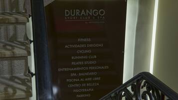 Señal que enumera los servicios de Durango Sport Club & Spa, que incluyen actividades de acondicionamiento físico, club de corredores, estudio de Pilates, entrenamiento personal, spa, piscina, centro de belleza, fisioterapia y estacionamiento.