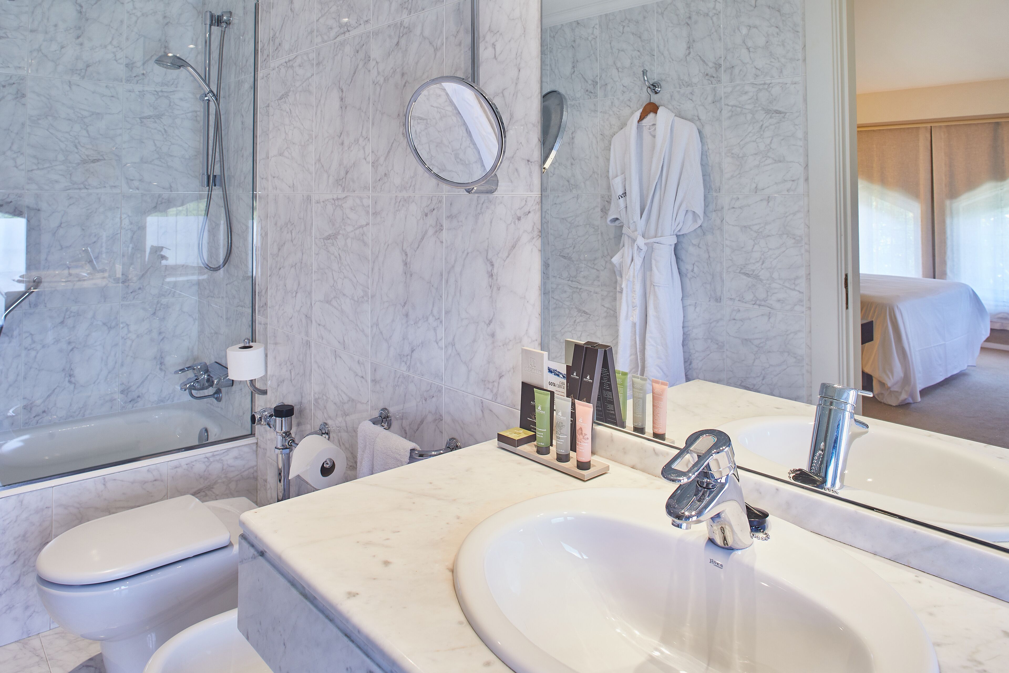 Un baño moderno con un espejo grande, una bañera, un inodoro y un lavamanos.