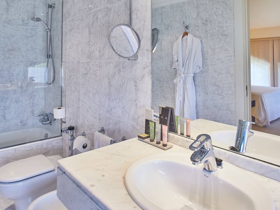 Ein modernes Badezimmer mit großem Spiegel, einer Badewanne, einer Toilette und einem Waschbecken.