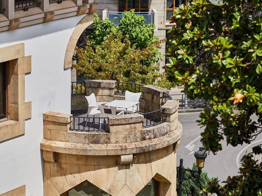 Um edifício com terraço no telhado, com área de estar ao ar livre e vista da rua.