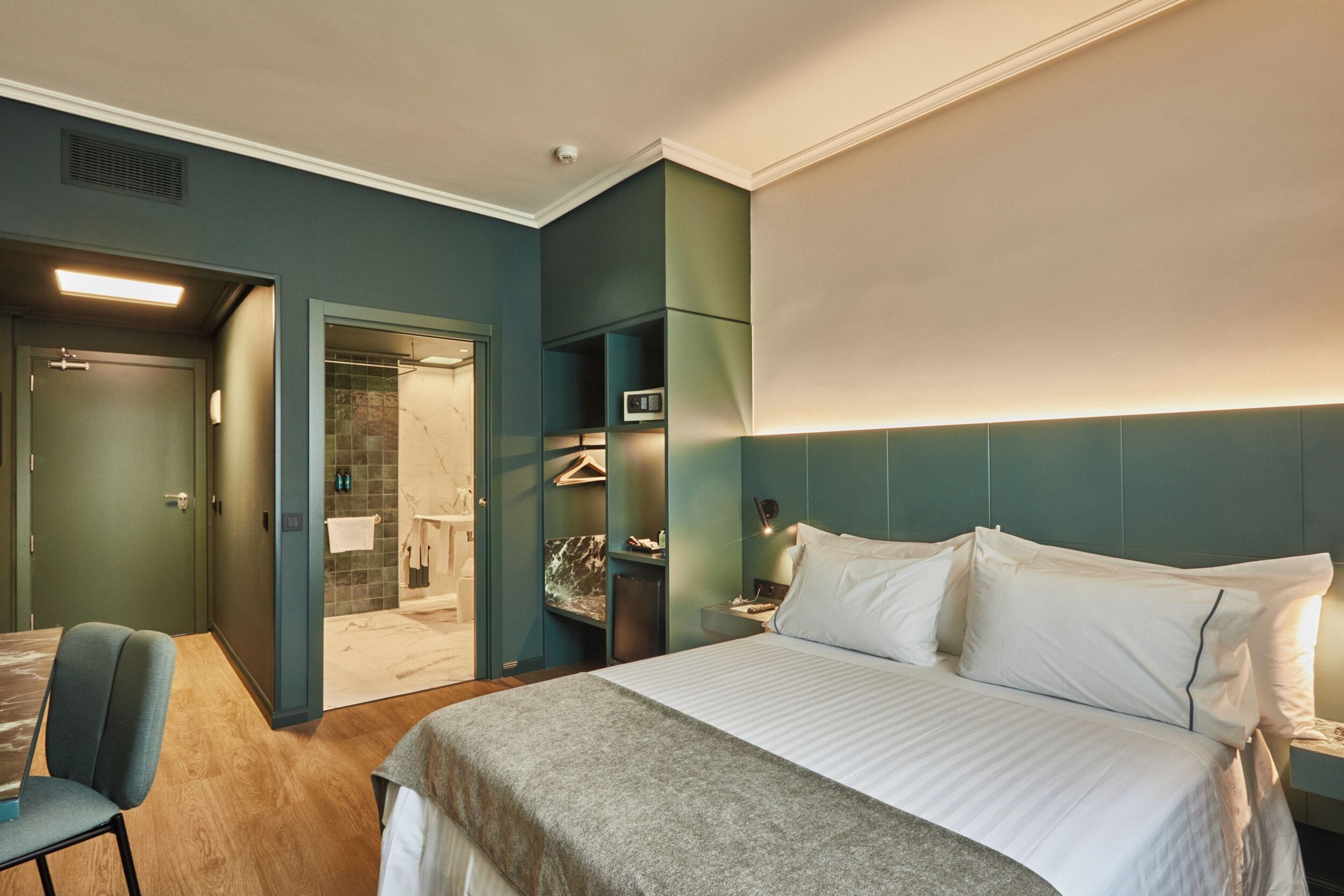 Una habitación de hotel con cama, una silla, armario y baño.