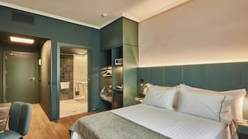 Una habitación de hotel con cama, una silla, armario y baño.