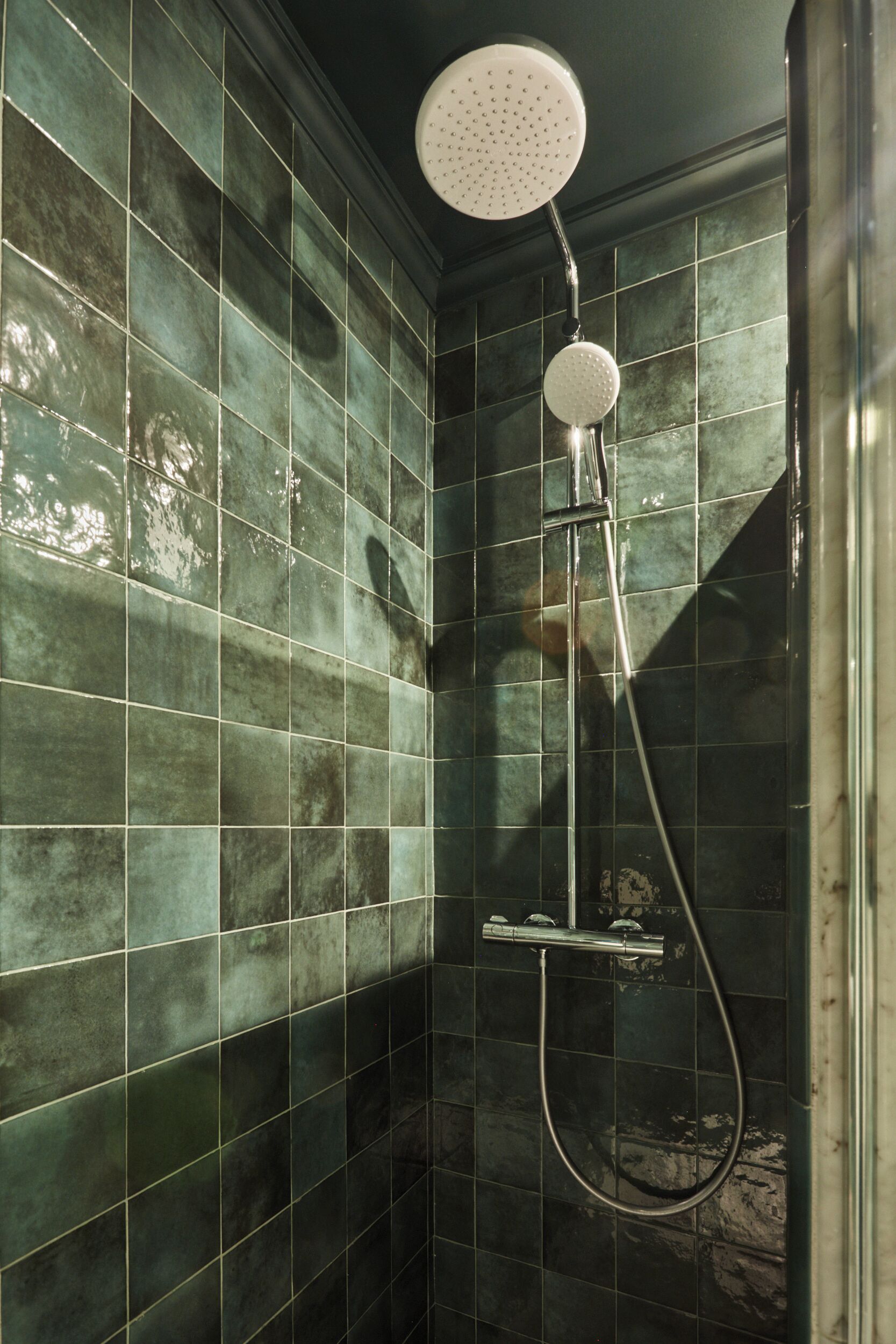 Une douche équipée d’un pommeau de douche à main et d’un robinet fixé au mur.