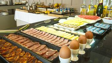 Un bufé con diversos alimentos, incluyendo carnes, quesos y frutas.