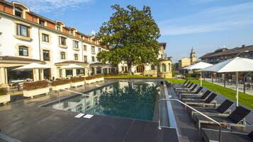 Een seizoensgebonden buitenzwembad en ligstoelen