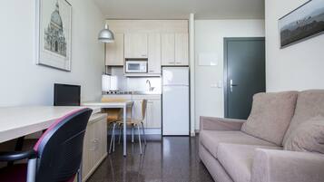 Een knus woongedeelte met kitchenette, eethoek en een bank.