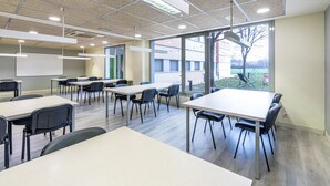 A conference room with tables and chairs, large windows, and a whiteboard. - Albergue Residencia Universitaria Resa Los Abedules - Campus Accomodation (Pamplona)