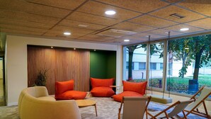A modern waiting area with a large window, a green accent wall, and orange seating. - Albergue Residencia Universitaria Resa Los Abedules - Campus Accomodation (Pamplona)