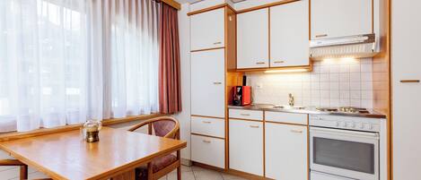 Una cocina compacta con una mesa de comedor, sillas, estufa y lavamanos.