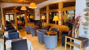 A cozy restaurant with wooden beams, round tables, and comfortable seating. - Alpenblick (Zermatt)