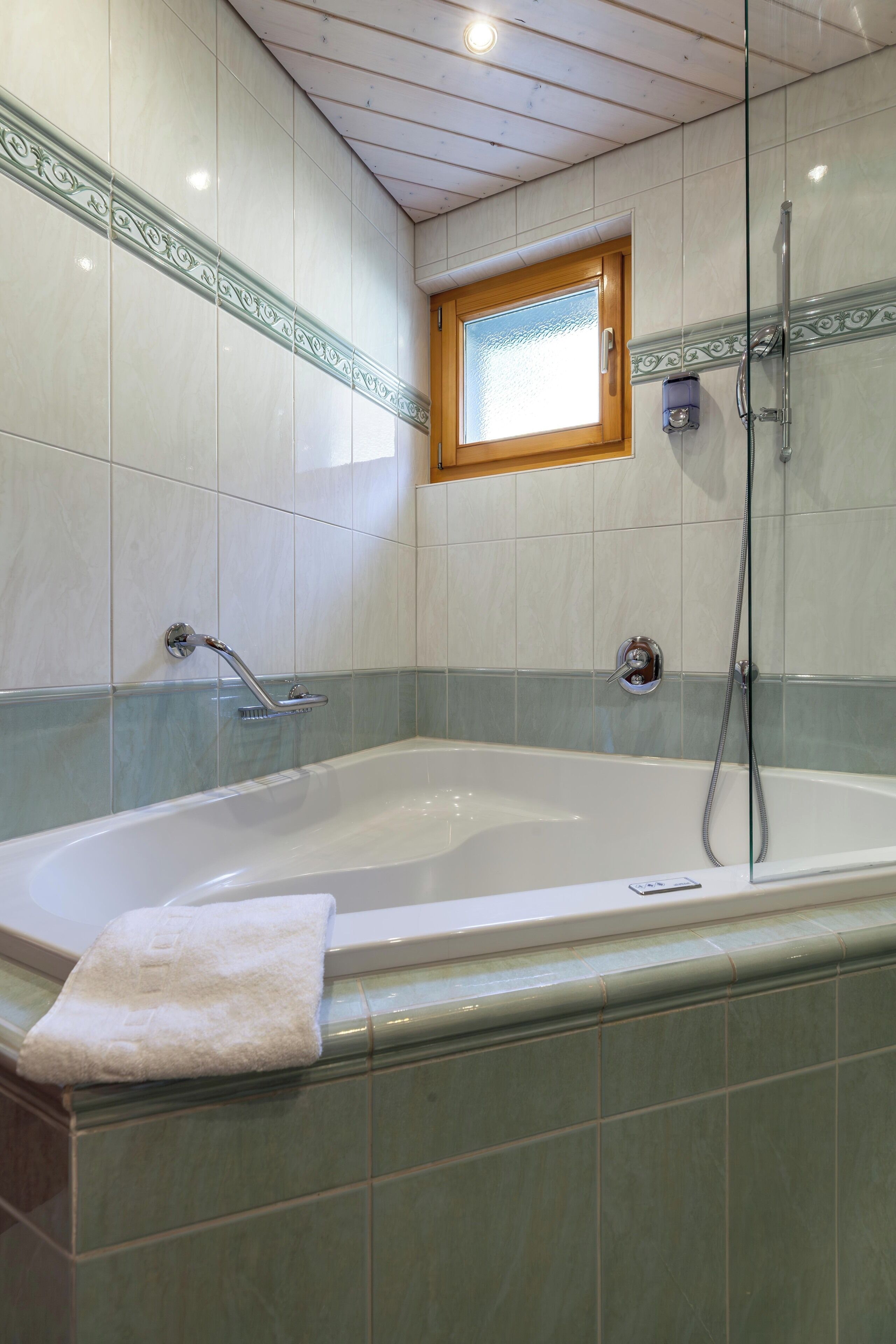 Ein Badezimmer mit einer großen Badewanne, einer Dusche und einem Fenster.