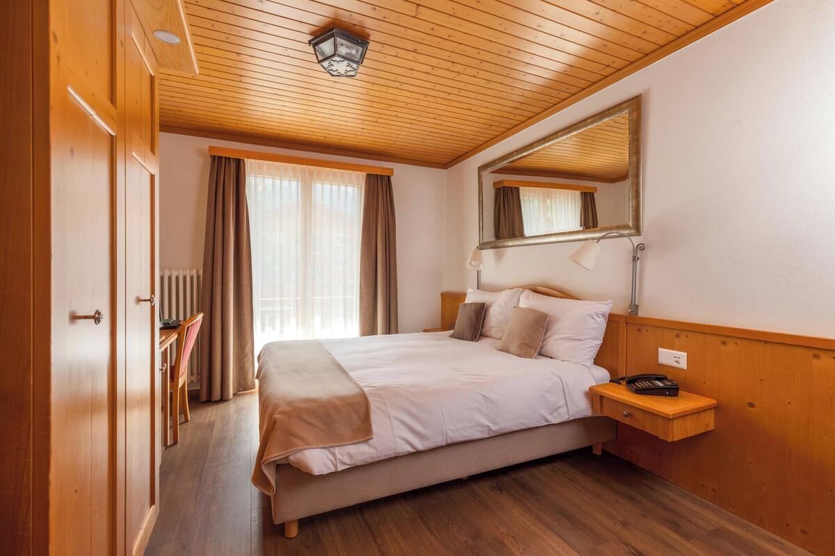 Un dormitorio ordenado con cama, mesita de noche y espejo.