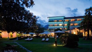 A hotel with a well-maintained lawn, outdoor seating area, and a multi-story building with balconies.