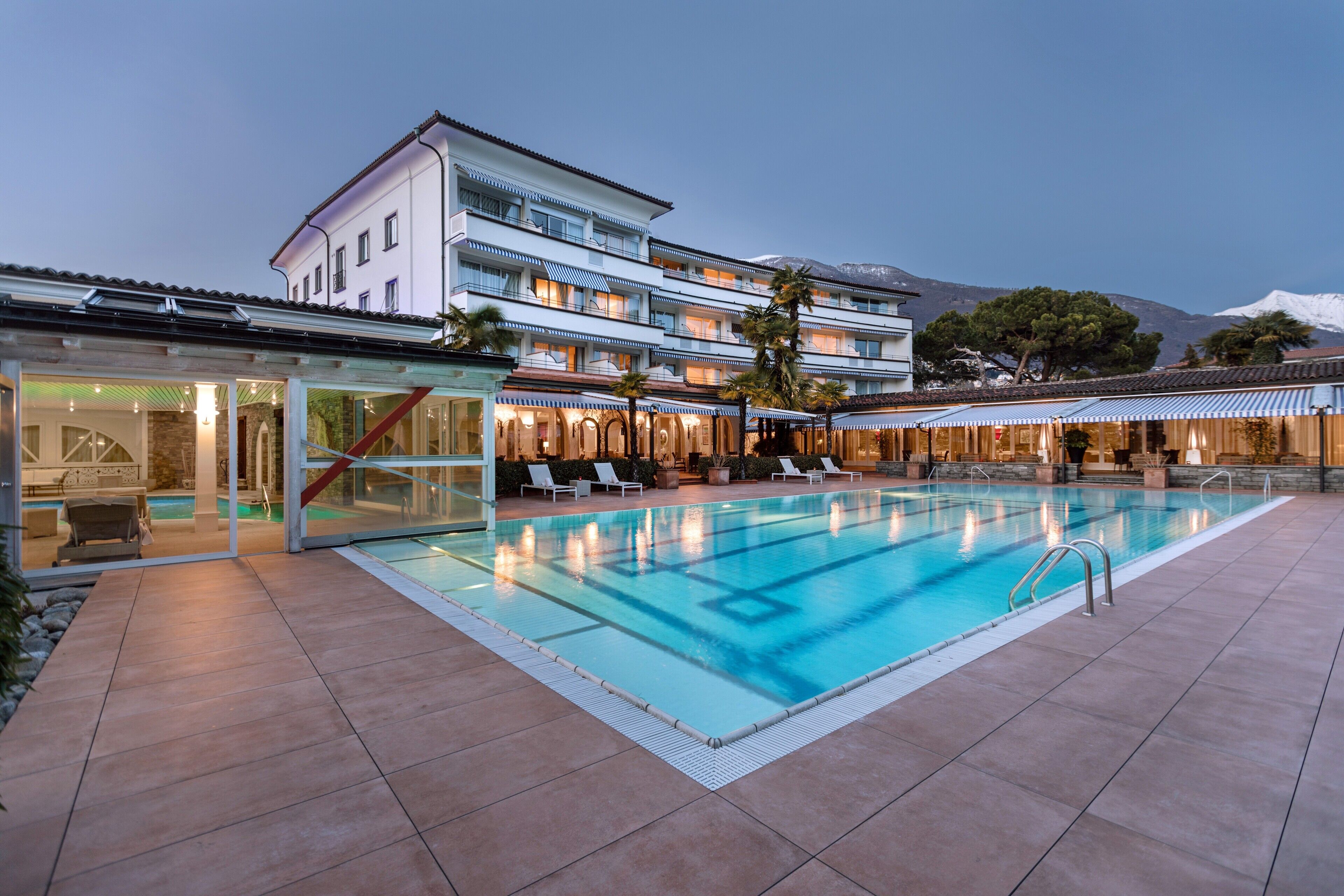 A hotel with a swimming pool, outdoor seating, and a mountain view.