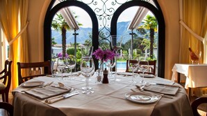 A table set for dining with a view of mountains and a pool.