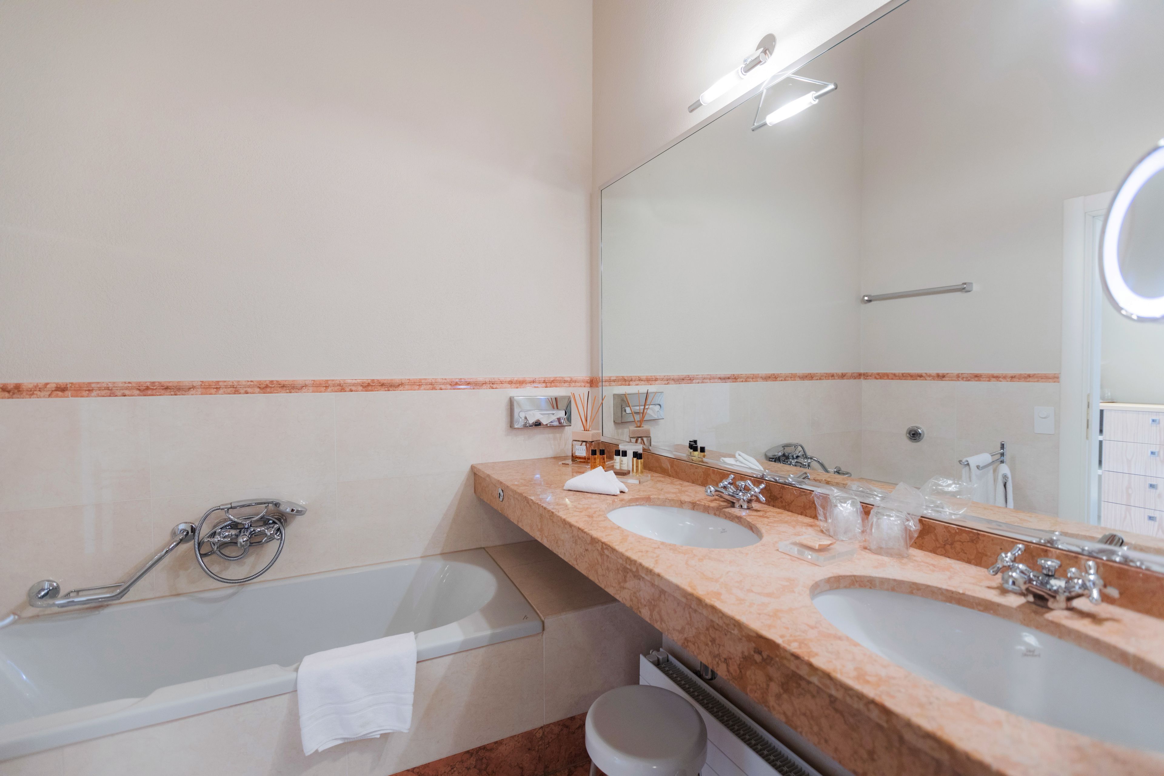 A bathroom with two sinks, a large mirror, and a bathtub.
