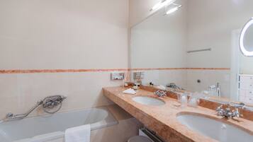 A bathroom with two sinks, a large mirror, and a bathtub.
