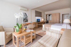 Una habitación de hotel moderna con cama, sofá, mesa de comedor y una pequeña cocina.