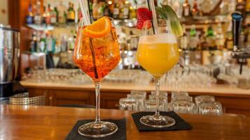 Zwei Cocktails auf einer Theke, im Hintergrund unscharf erkennbare Flaschen und Gläser.
