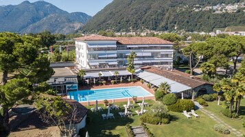 A resort with a swimming pool, outdoor seating, and a mountainous backdrop.