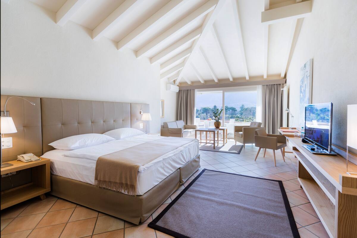 Une chambre d’hôtel avec un grand lit, une télévision, un bureau et un balcon avec vue.