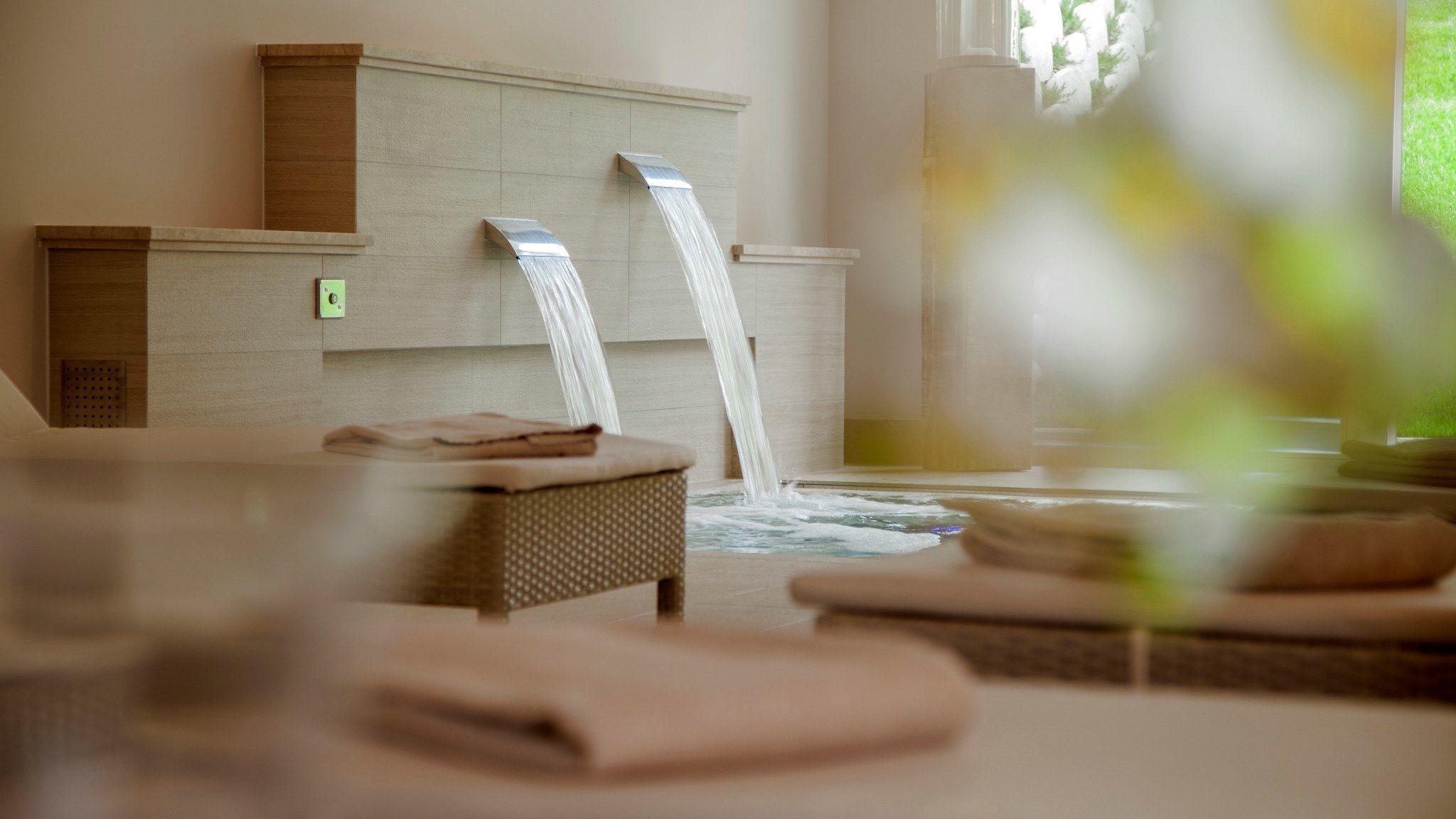 A spa room with two water features, a massage table, and towels.