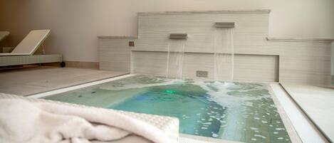 Un cuarto de spa con un jacuzzi, un reloj en la pared y una cama en la esquina.