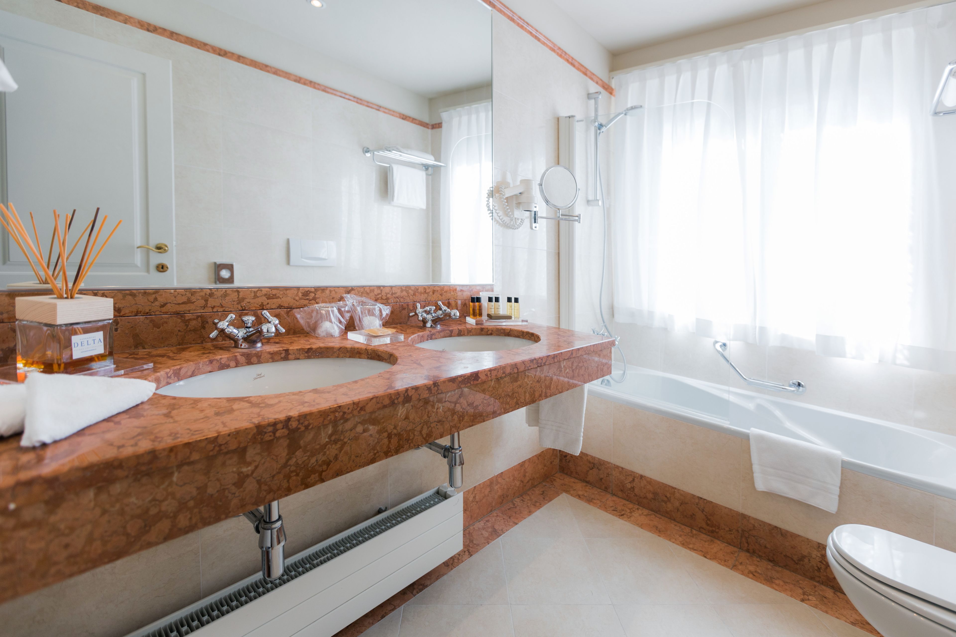 Een moderne badkamer met twee wasbakken, een bad en een grote spiegel.